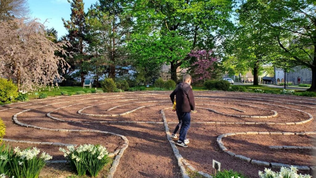 a young boy runs around a stone labyrinth during early spring