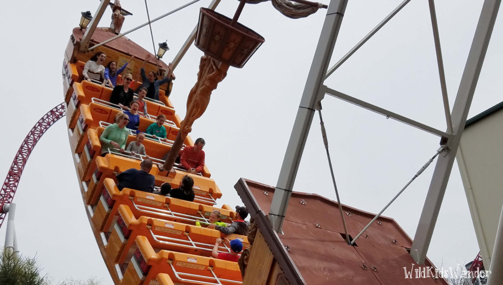 people sit on a "pirate ship" ride as they swing high