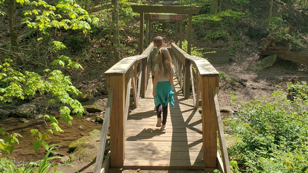 Family-Friendly hikes near Philadelphia - two kids crossing wooden bridge over Potter Run Creek on Tyler Park's nature trail