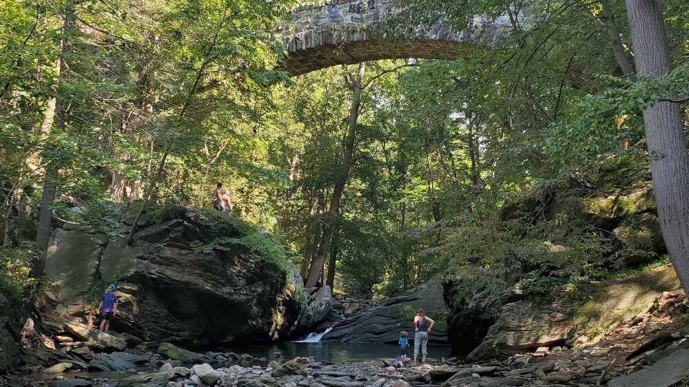 Family-Friendly hikes near Philadelphia.  Hikers gathered near the Devil's Pool with bridge overhead at Wissahickon Valley Park