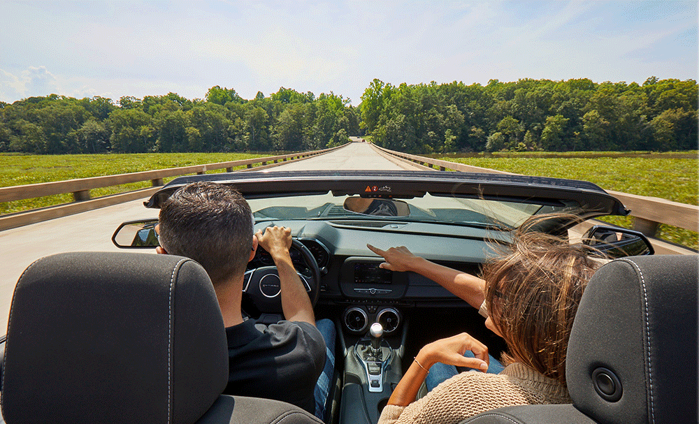 Driver and passenger in convertible car driving to the free Jamestown-Scotland Ferry and the Founder's District in Virginia