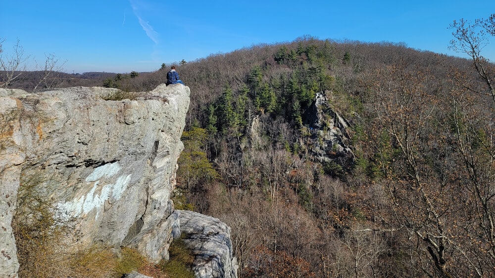 View of man sitting on outcropping at Rocks State Park in Maryland
