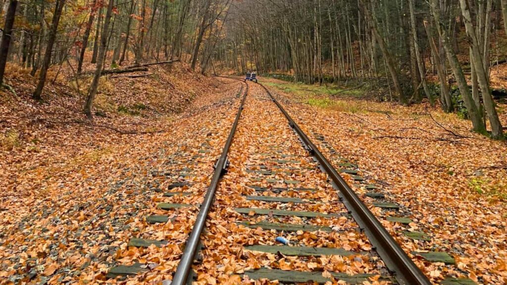 two people ride a special bike on old train tracks during the fall