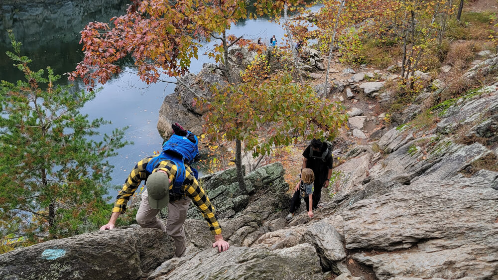 man climbs up a 50-foot ascent on a cliff with Potomac River below