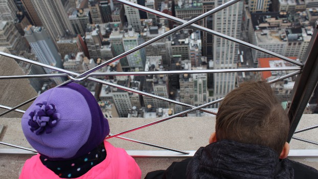 Two kids looking out from the Empire State Building as they enjoy visiting New York City in Winter