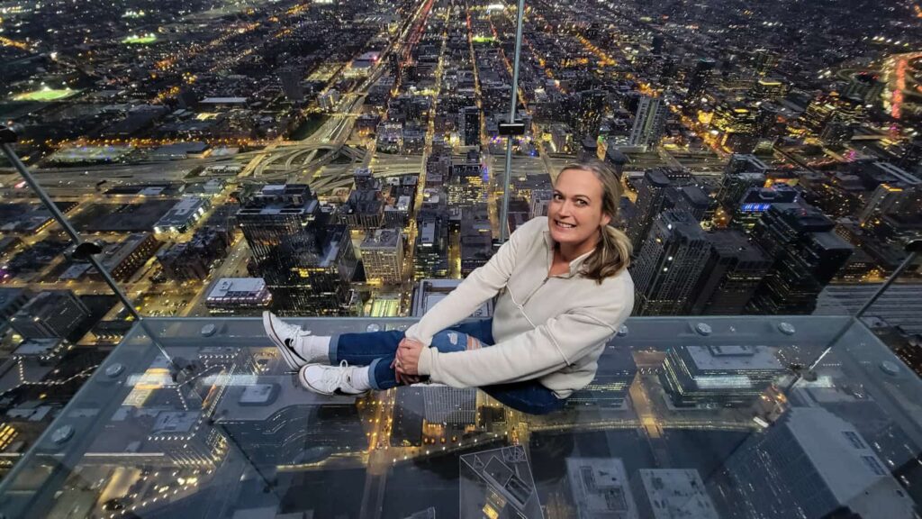 Woman sits on the glass bottom of the Ledge at the Willis Tower