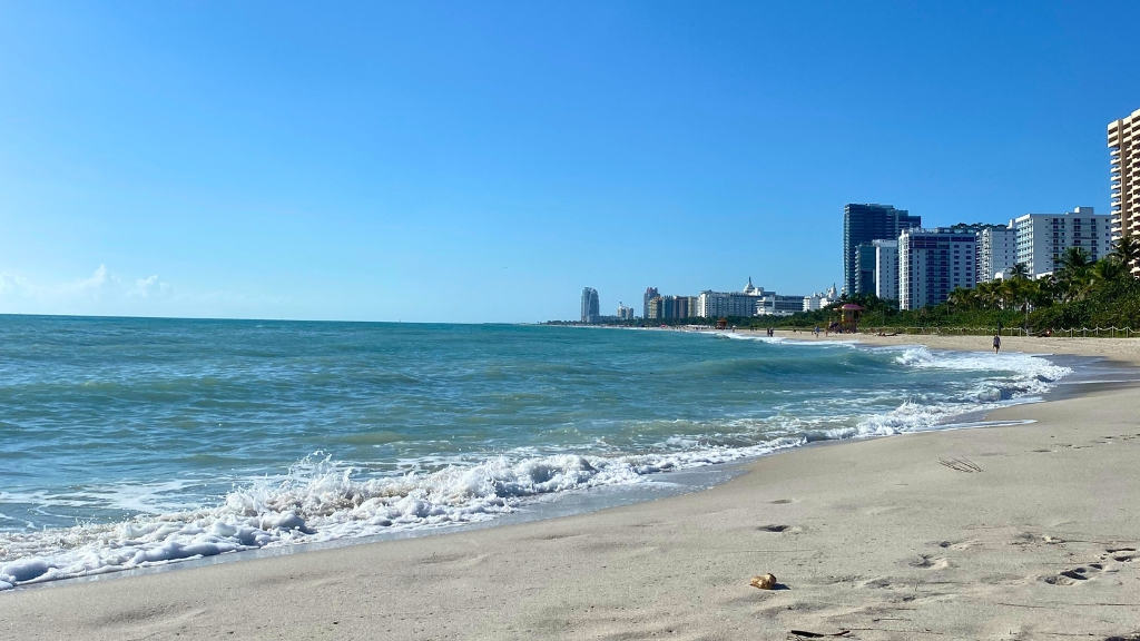 View of Miami Skyline from the beach with the ocean and sand in the foreground