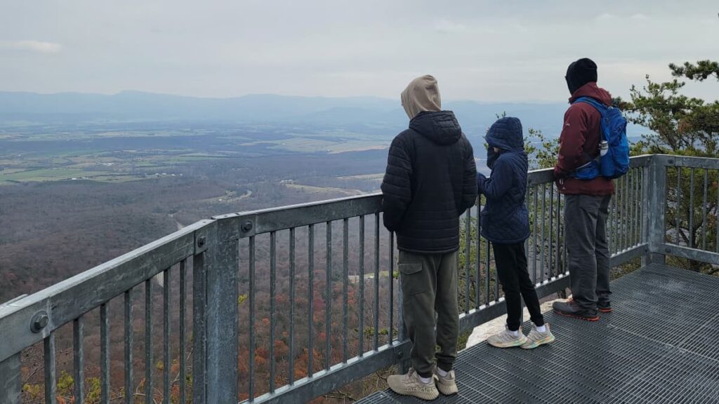 Three people look out over the Page Valley and Blue Ridge Mountains from the Massanutten Storybook Trail overlook