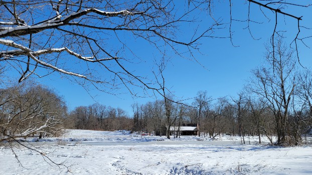 view of a barn in the distance with snow on the ground