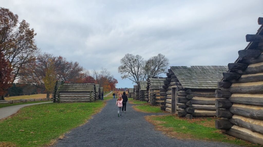 Two kids walk along the path between cabins at Valley Forge National Historical Park