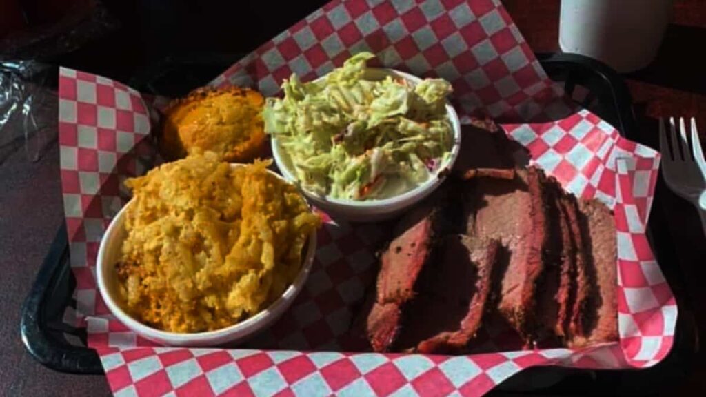 A rectangle tray holds brisket, cole slaw, and cornbread