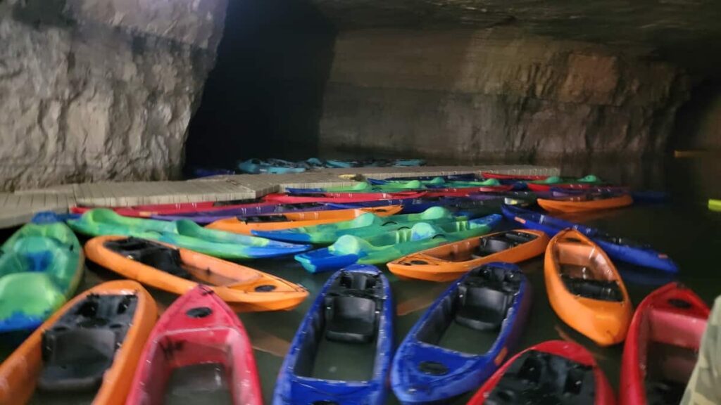 unused kayaks float on the water inside a cave
