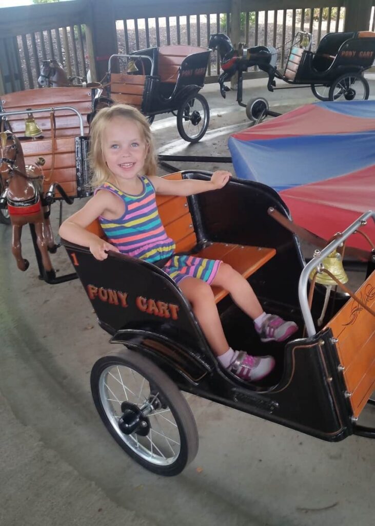 Little girl sits on carriage of horse and carriage ride in Hersheypark