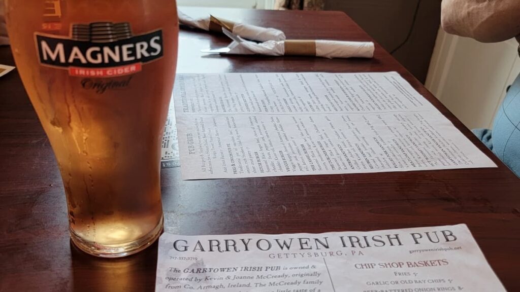 A glass of Magners Cider sits on a restaurant table next to the menu with "Garryowen Irish Pub" written at the top