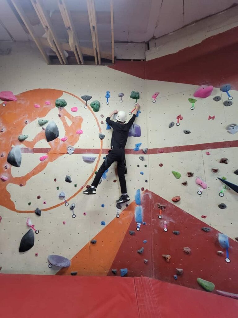 a young boy climbs on wall at an indoor rock climbing gym