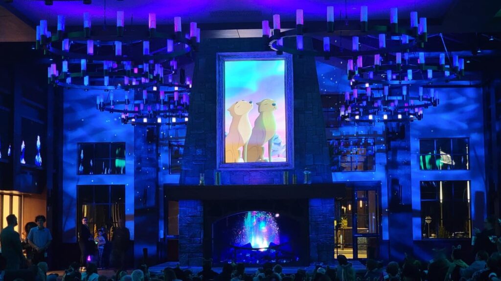 the lobby of great wolf lodge glows blue at night with a cartoon wolf on a screen above the fireplace