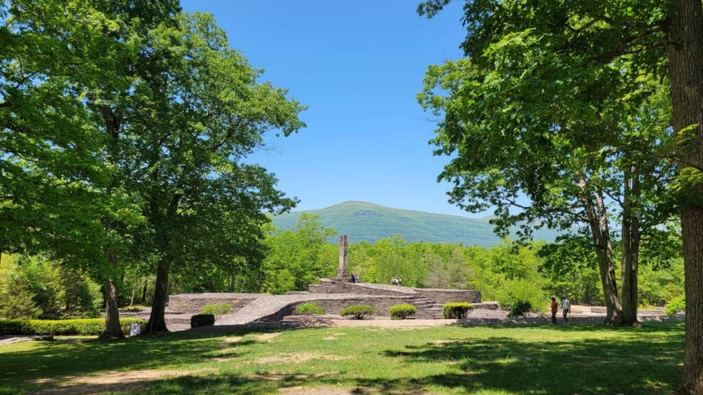 A distance view of the bluestone sculpture as seen through the trees