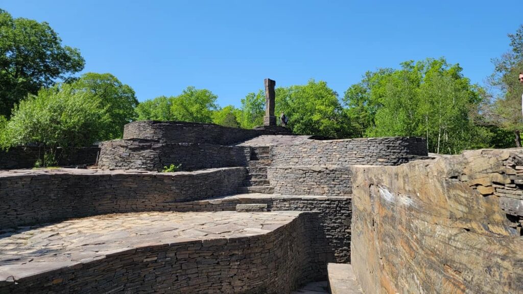 multi-level platforms and stairs made from blue stone are centered in the photo with a large center monolith towards the back