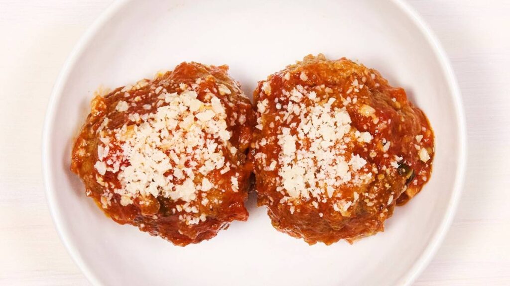 two large meatballs sit on a white plate