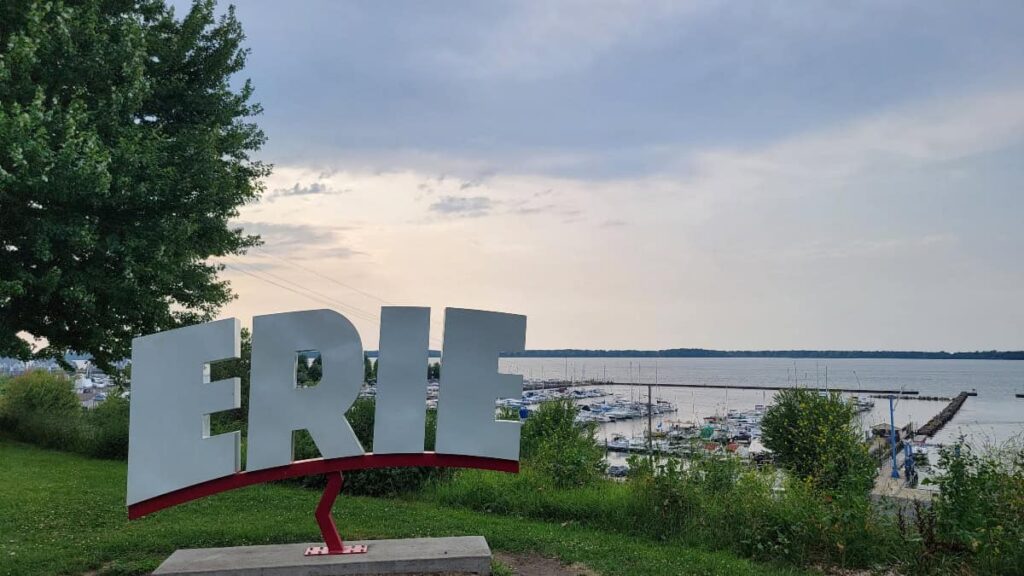 large white letters spell out "ERIE" with a harbor in the background