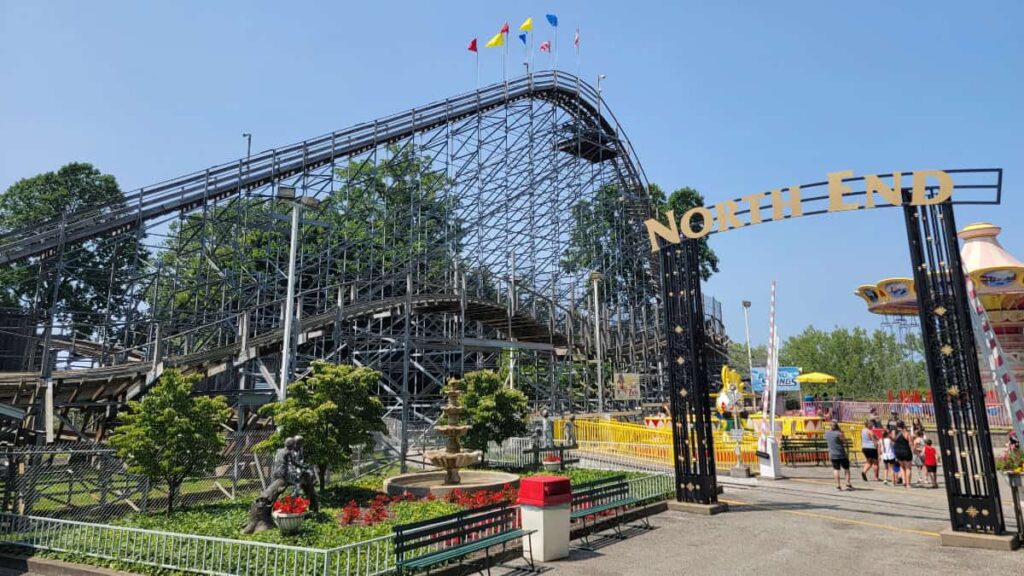 view of a wooden rollercoaster with multicolor flags at the top