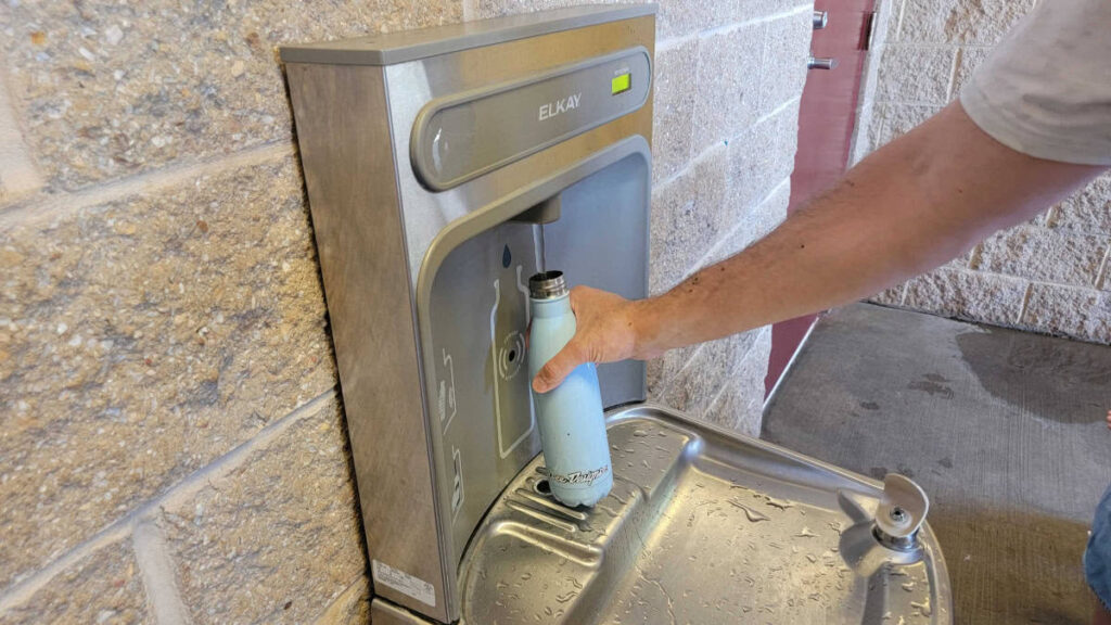 A water bottle is filled at a water fountain