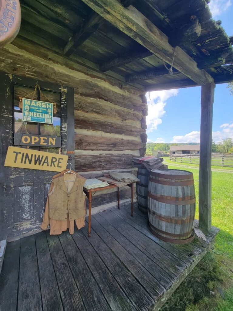 A log cabin porch shows off a barrel and clothing for purchase