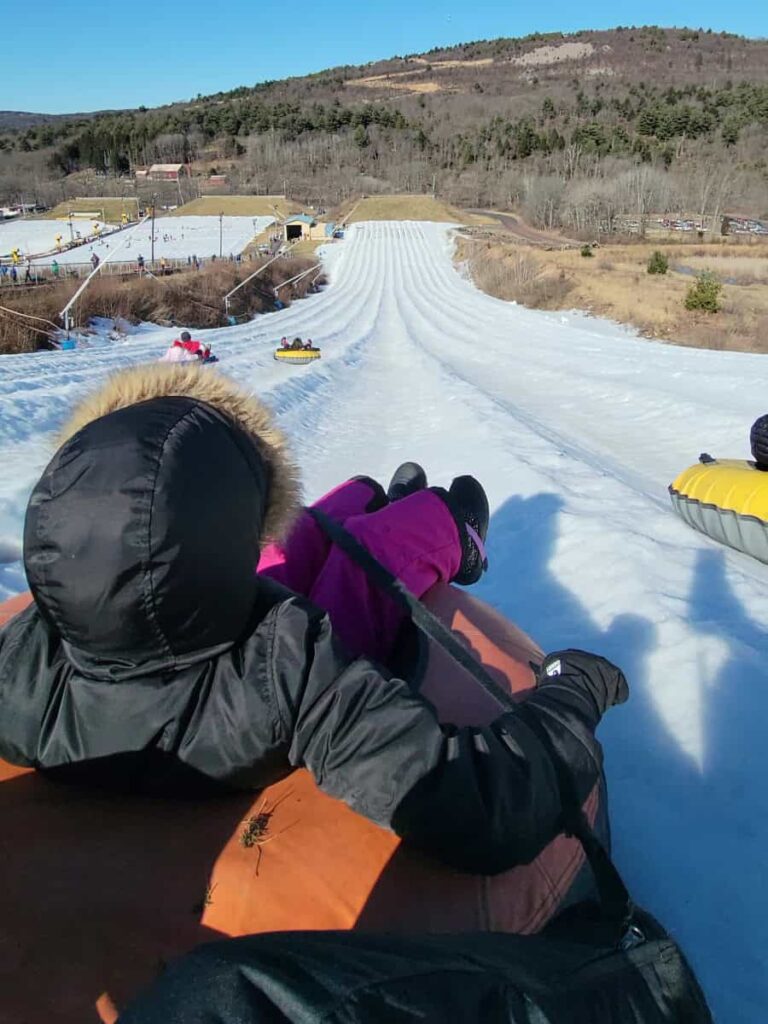 a young girl sits in a snow tube at the top of the mountain 