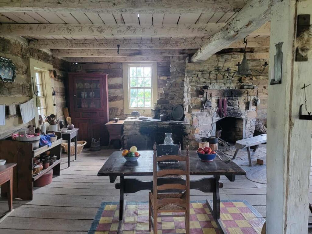 View inside the Biddle House at Old Bedford Village with a table set for dinner and a stone fireplace in the back