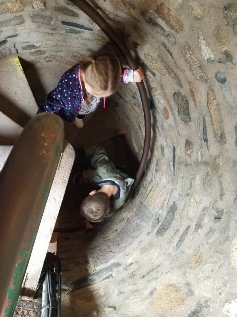 Two kids walk down corkscrew stone steps inside Bowman's Hill Tower