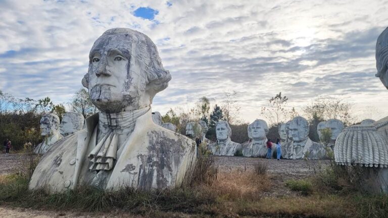 a tall bust of george washington sits in front of other presidents heads statues