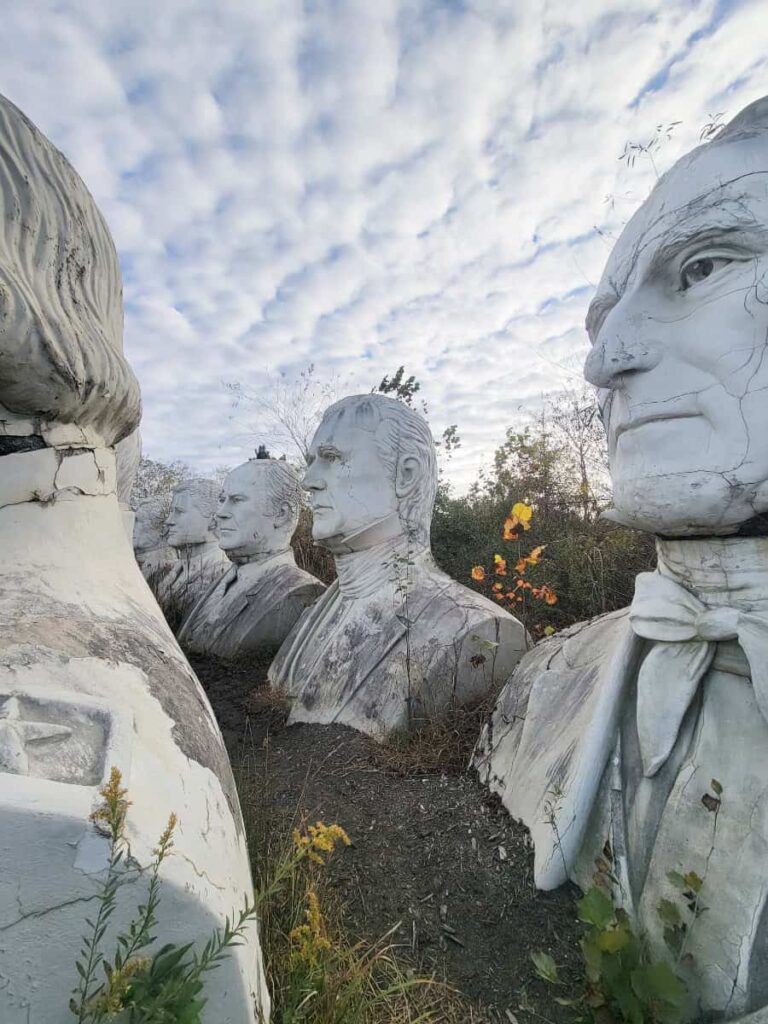 tall white statues of US presidents sit in a field