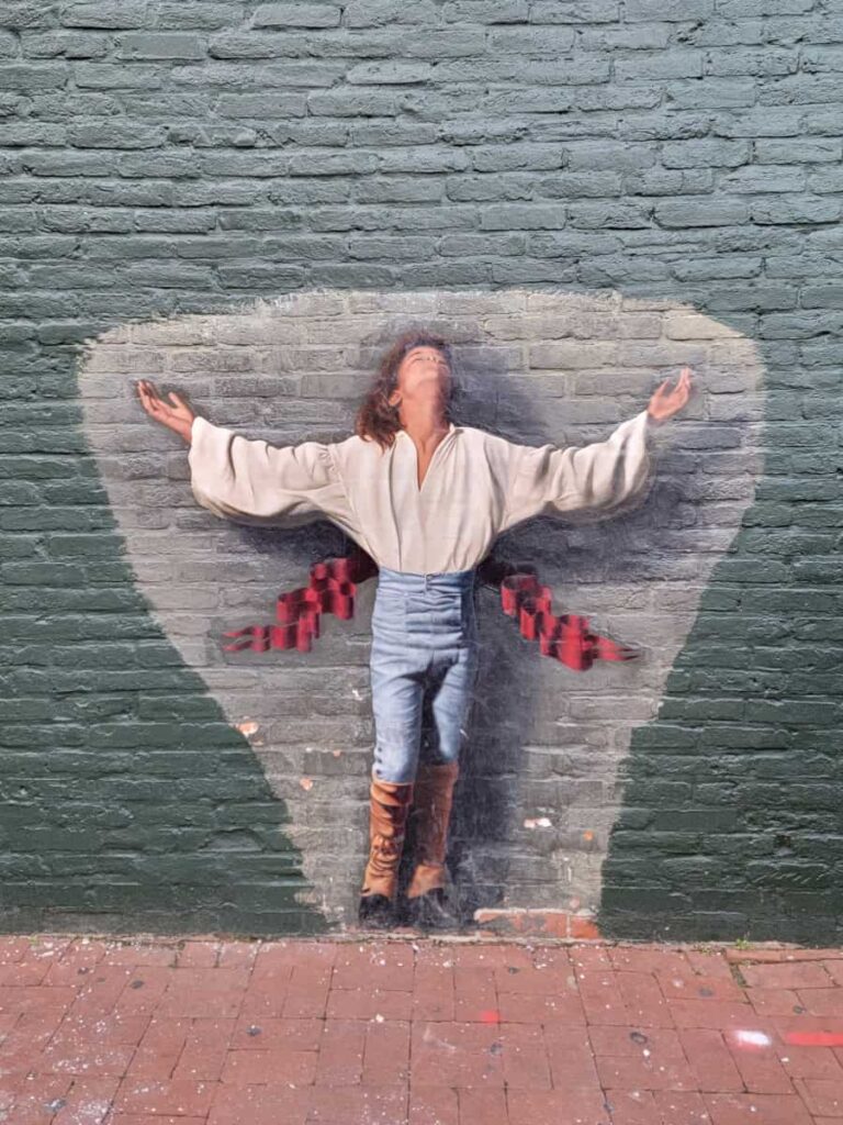 painted mural of a person wearing a white shirt and jeans with arms outstretched