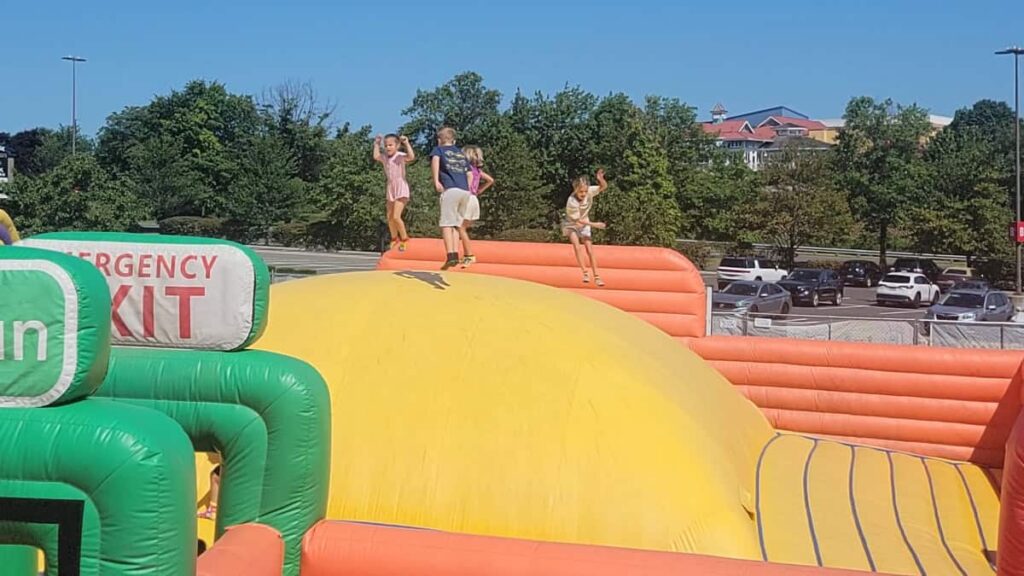 kids jump on a massive yellow bouncy "pillow"